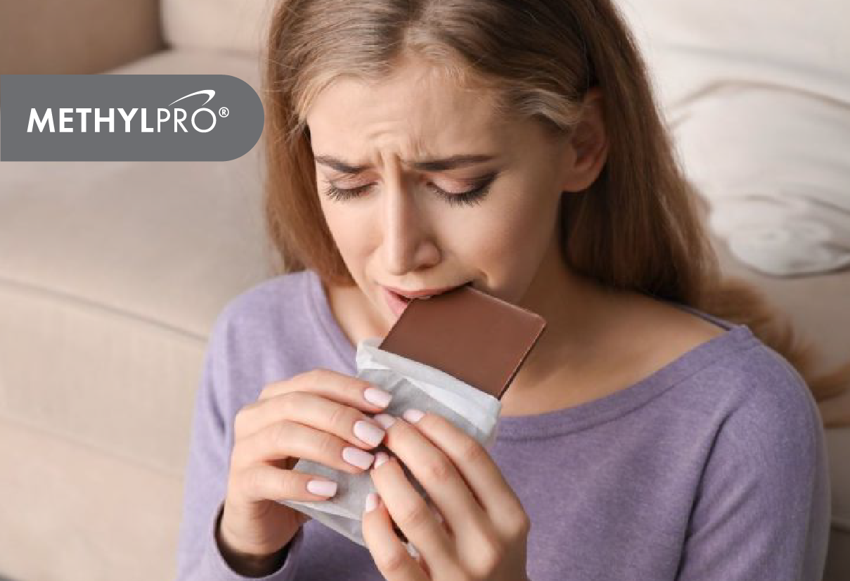 Woman biting a chocolate bar in a casual purple top with MethylPro logo overlay