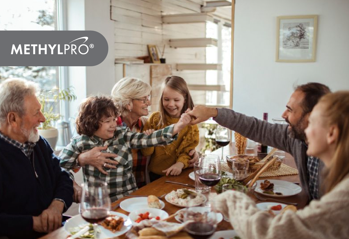 Multigenerational family toasting at a holiday dinner with MethylPro logo in the corner.