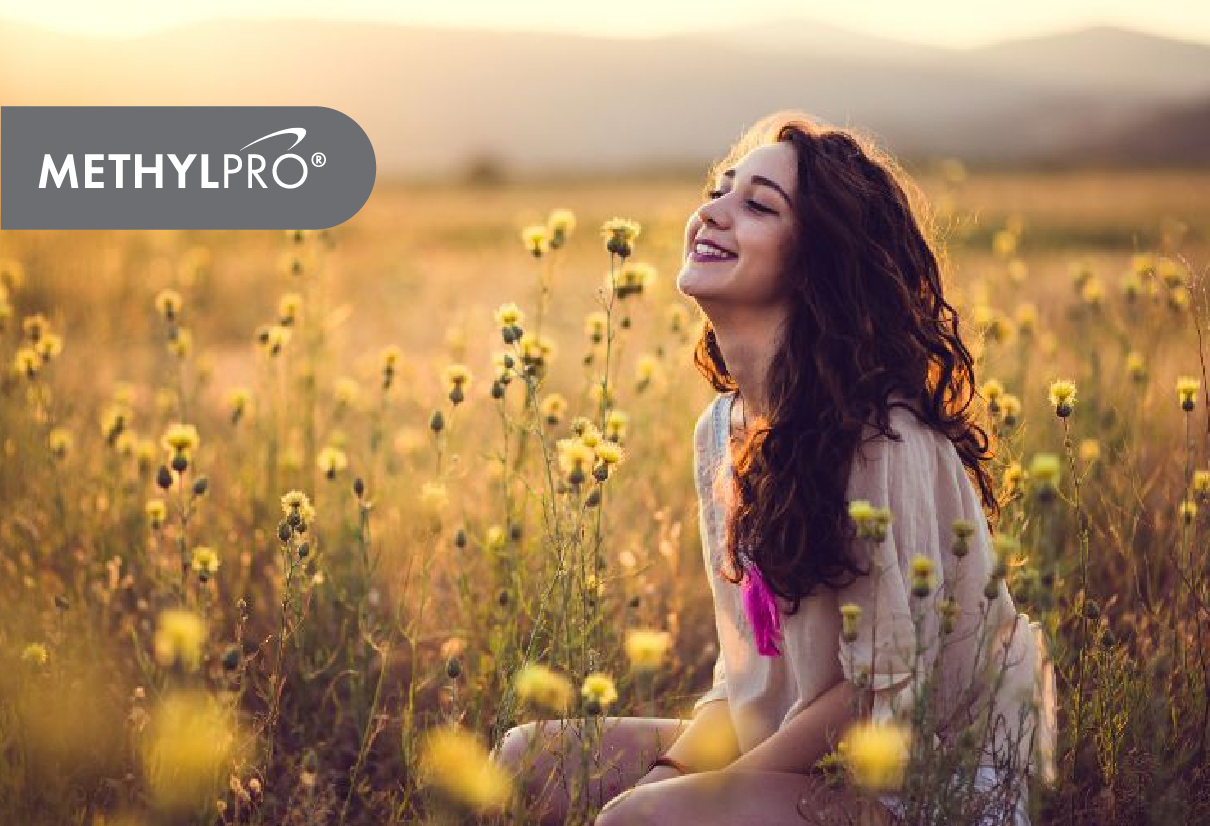 Smiling woman in a sunlit field of yellow wildflowers enjoying nature