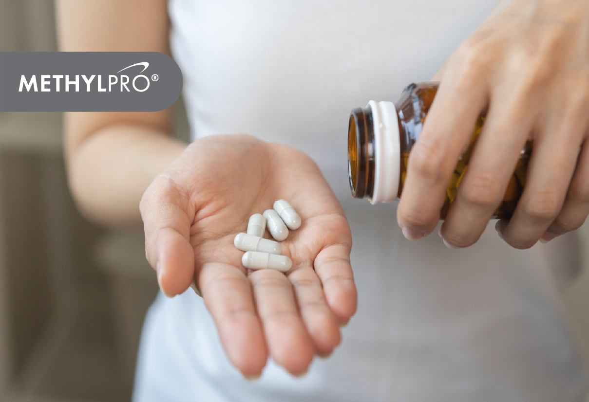 A person pours white capsules from a brown bottle into their cupped palm, with a MethylPro logo overlay.