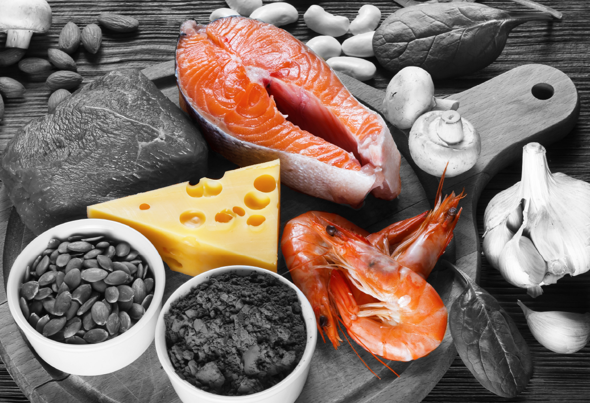 Assorted selenium and iodine rich foods including salmon cheese shrimp and nuts on a wooden cutting board