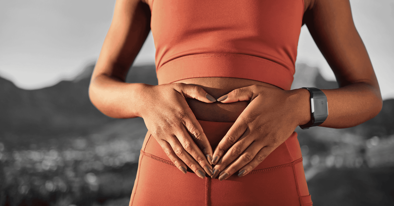 Athlete in orange activewear forms a heart shape with their hands over the midriff to symbolize metabolic health.