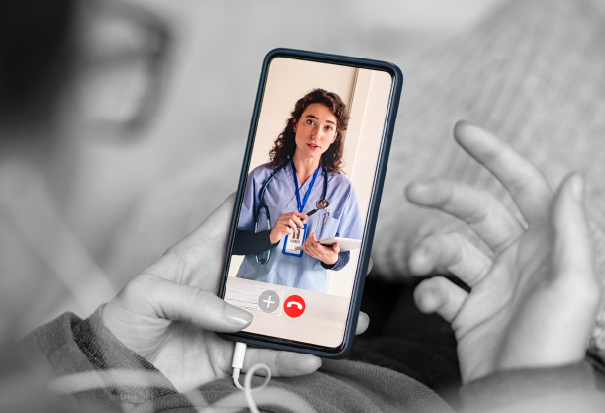 Healthcare professional appears on a smartphone screen during a telehealth video call.