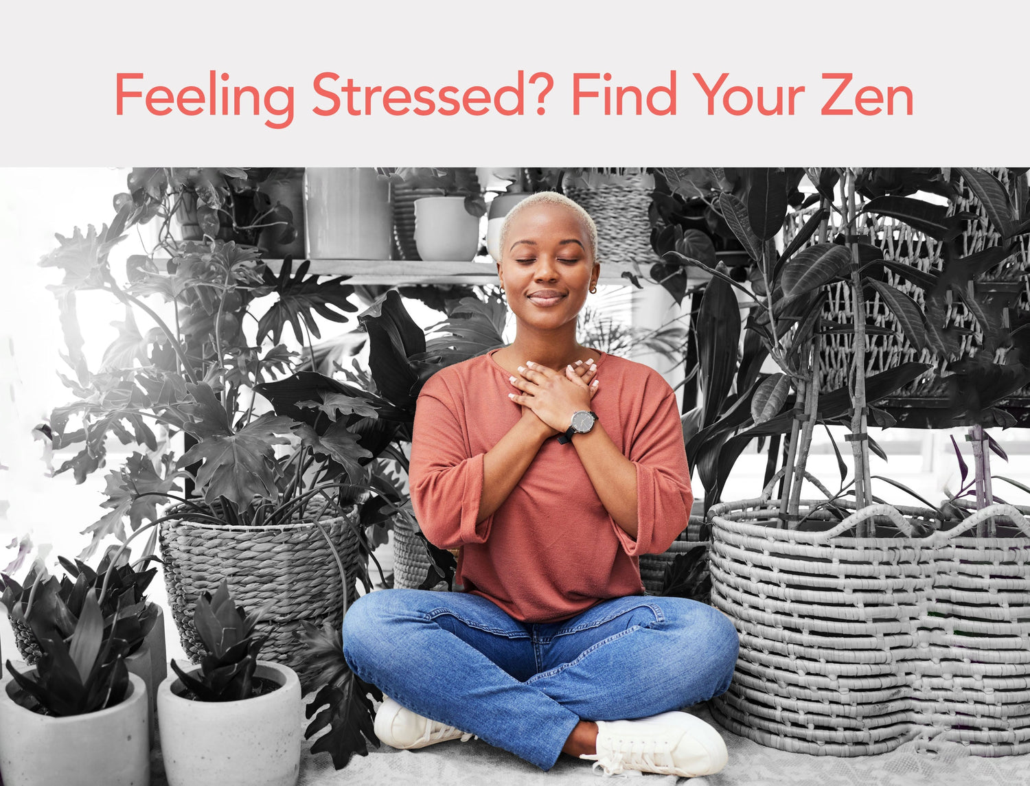 Woman sits cross-legged among houseplants with eyes closed and hands over her heart while meditating