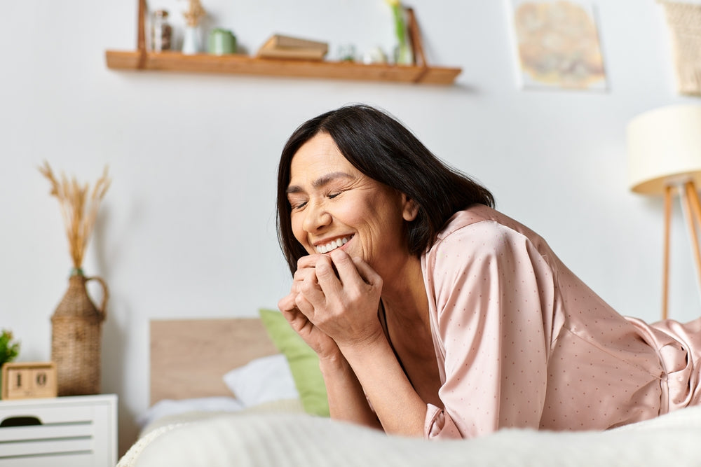 Smiling woman in a pink robe relaxing on a bed at home, illustrating wellbeing after hysterectomy