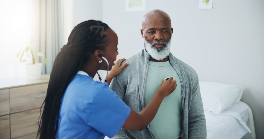 Nurse checks the elderly man's chest with a stethoscope in a bedroom.