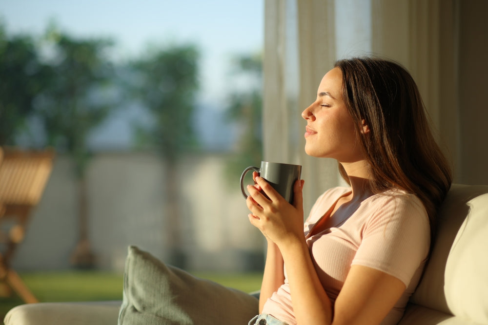 Woman relaxing with a mug in a sunlit living room, illustrating a wellness moment for a nutrition article.