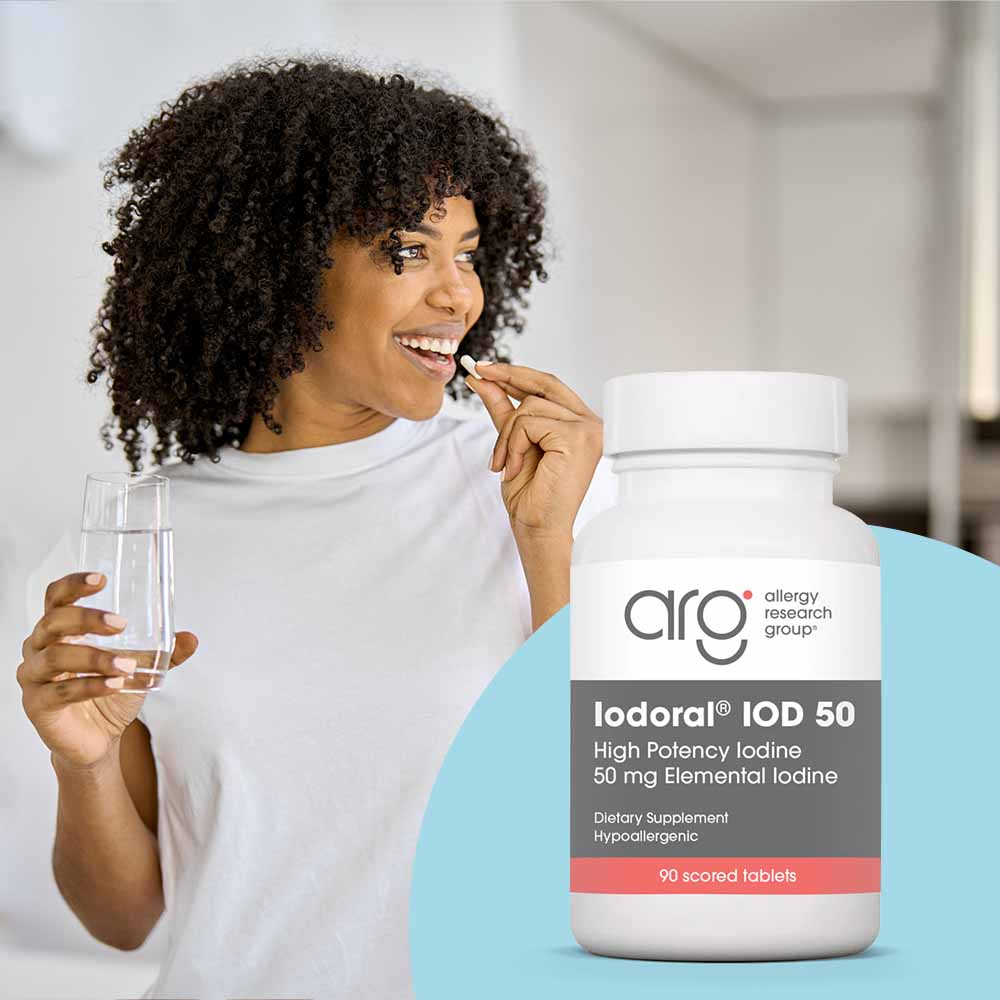 Woman holding a glass of water next to a bottle of Allergy Research Group iodine supplement.