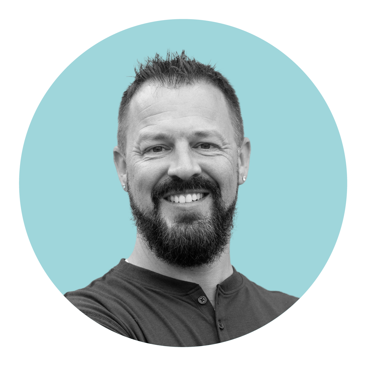 Man with a beard and mustache smiling against a light blue background