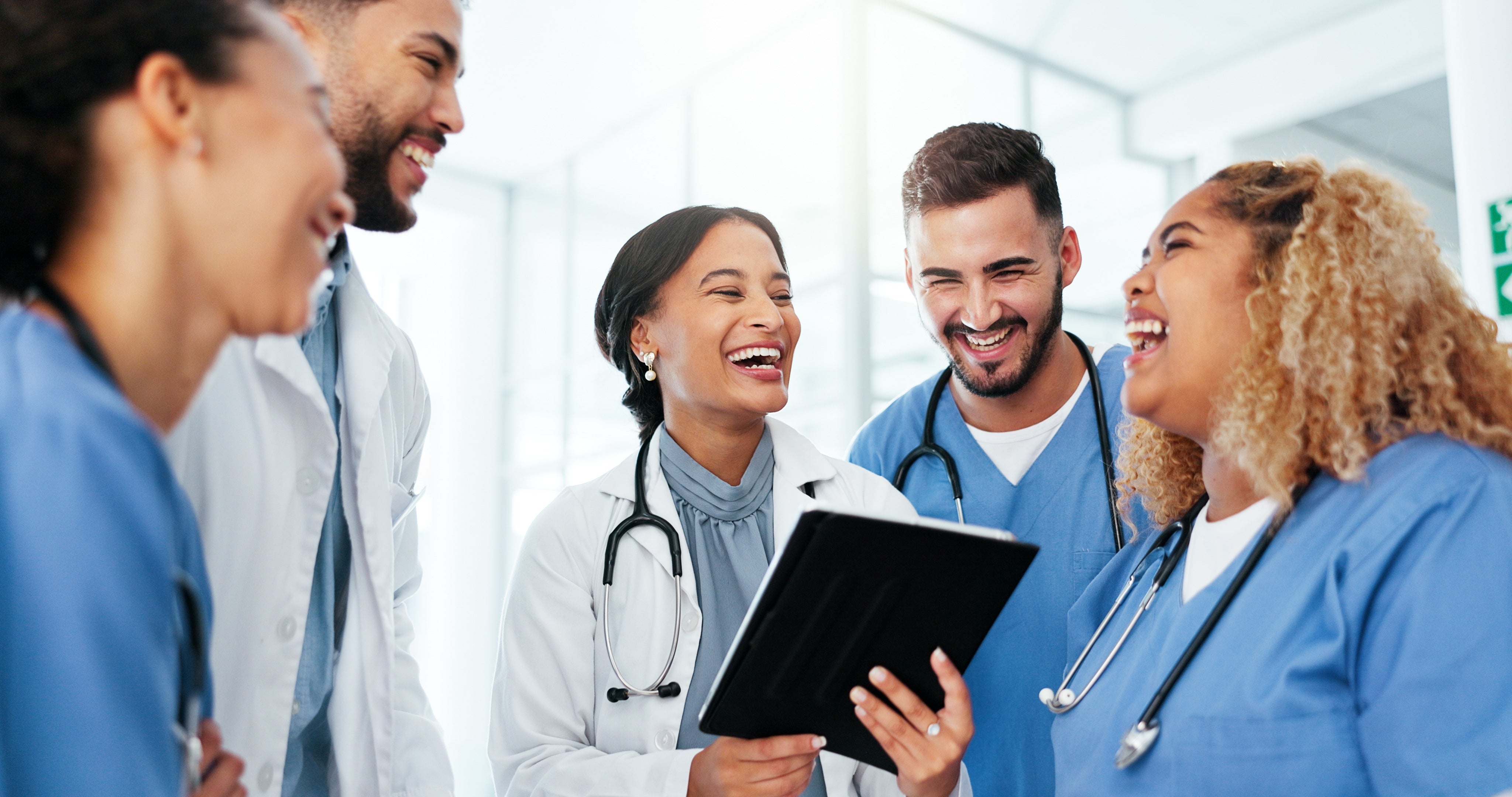 Group of medical professionals in a hospital setting, smiling and interacting.