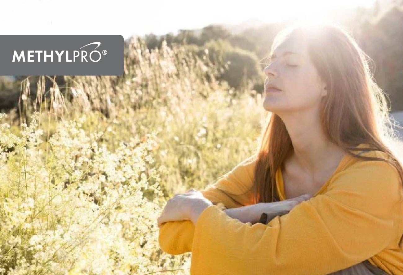 Woman in a sunlit field with eyes closed, basking in sunlight for vitamin D mood support; MethylPro logo visible.